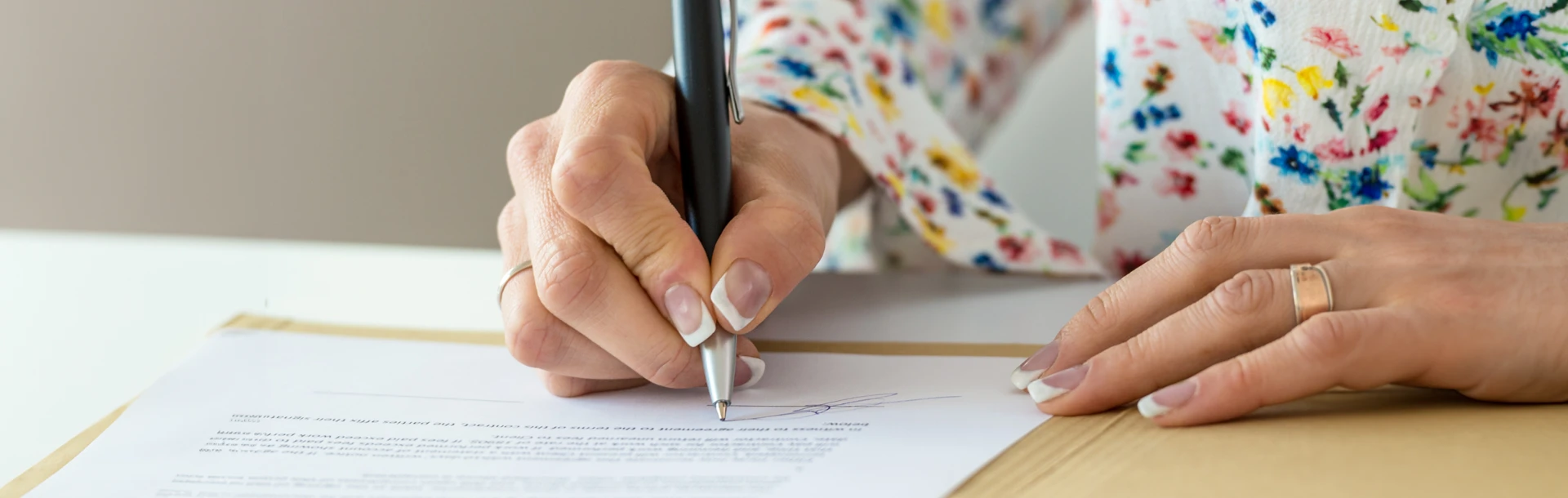 A woman sat at a desk using a pen to write on documents.