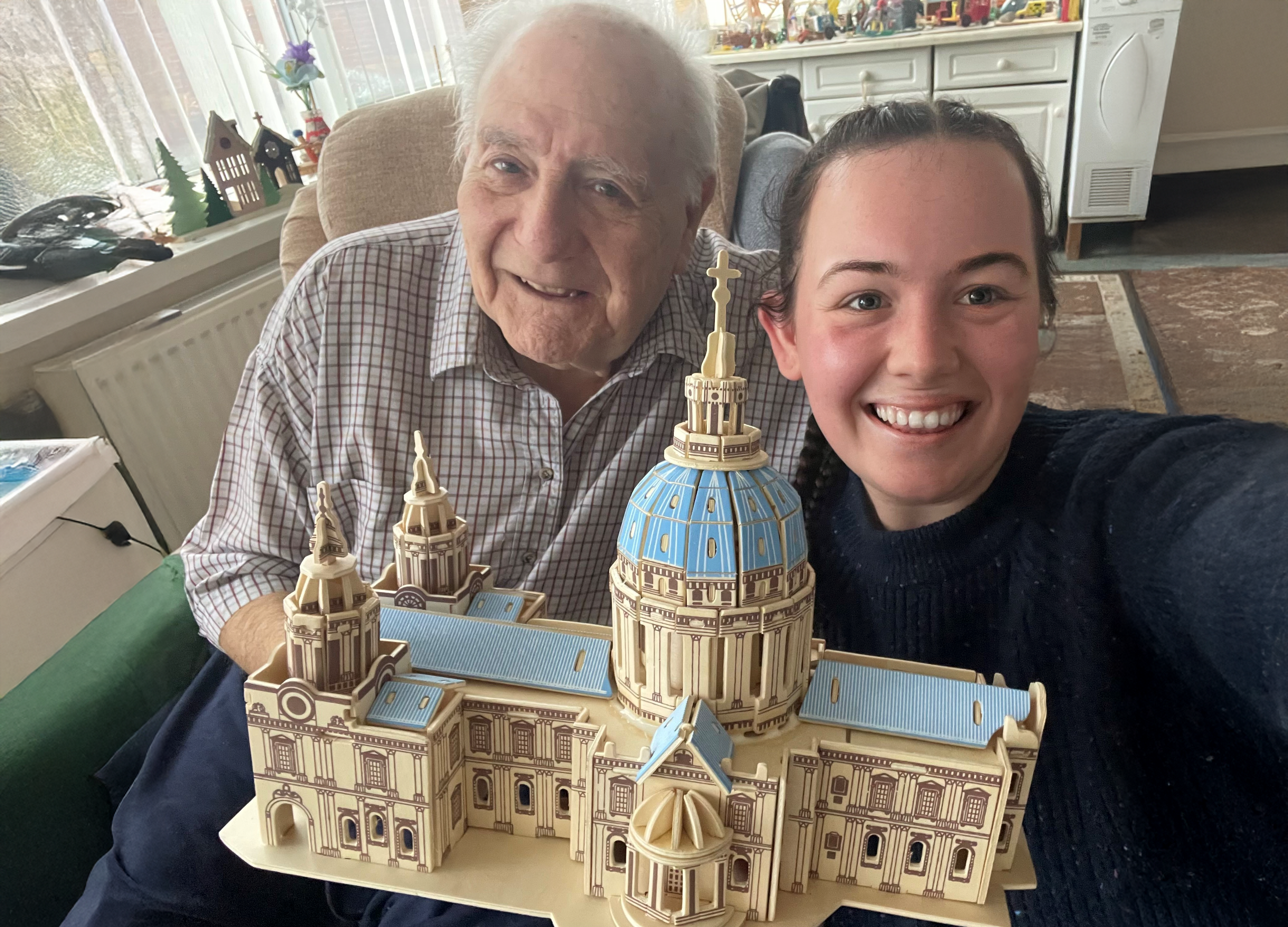 Blind veteran Maurice and volunteer Mia smile and look into camera while holding the cathedral model