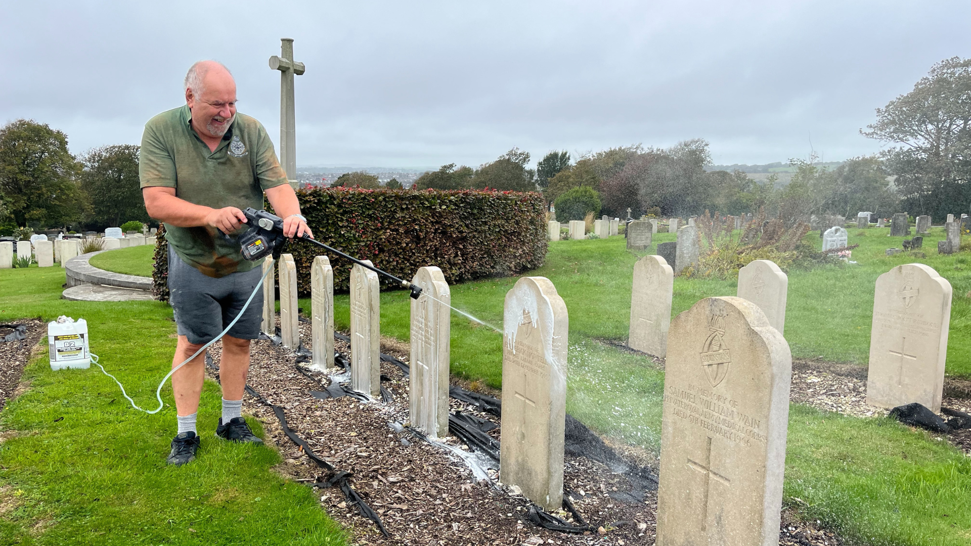 Steve in the Brighton Cemetery using a power washer on the head stones and smiling