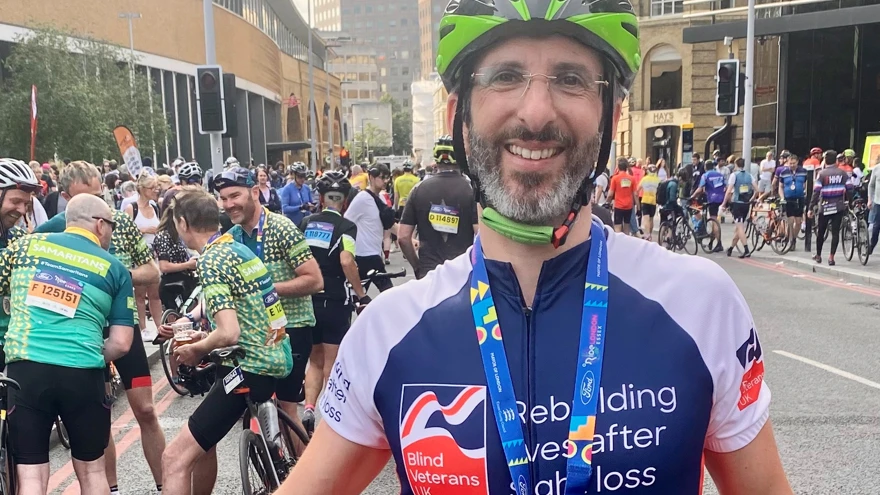 Rob standing with his bike and wearing his medal for completing the cycle