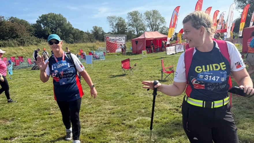 Jan and Poppy in their Blind Veterans UK T-shirts. Poppy is walking slightly ahead of Jan and turning back to talk to her