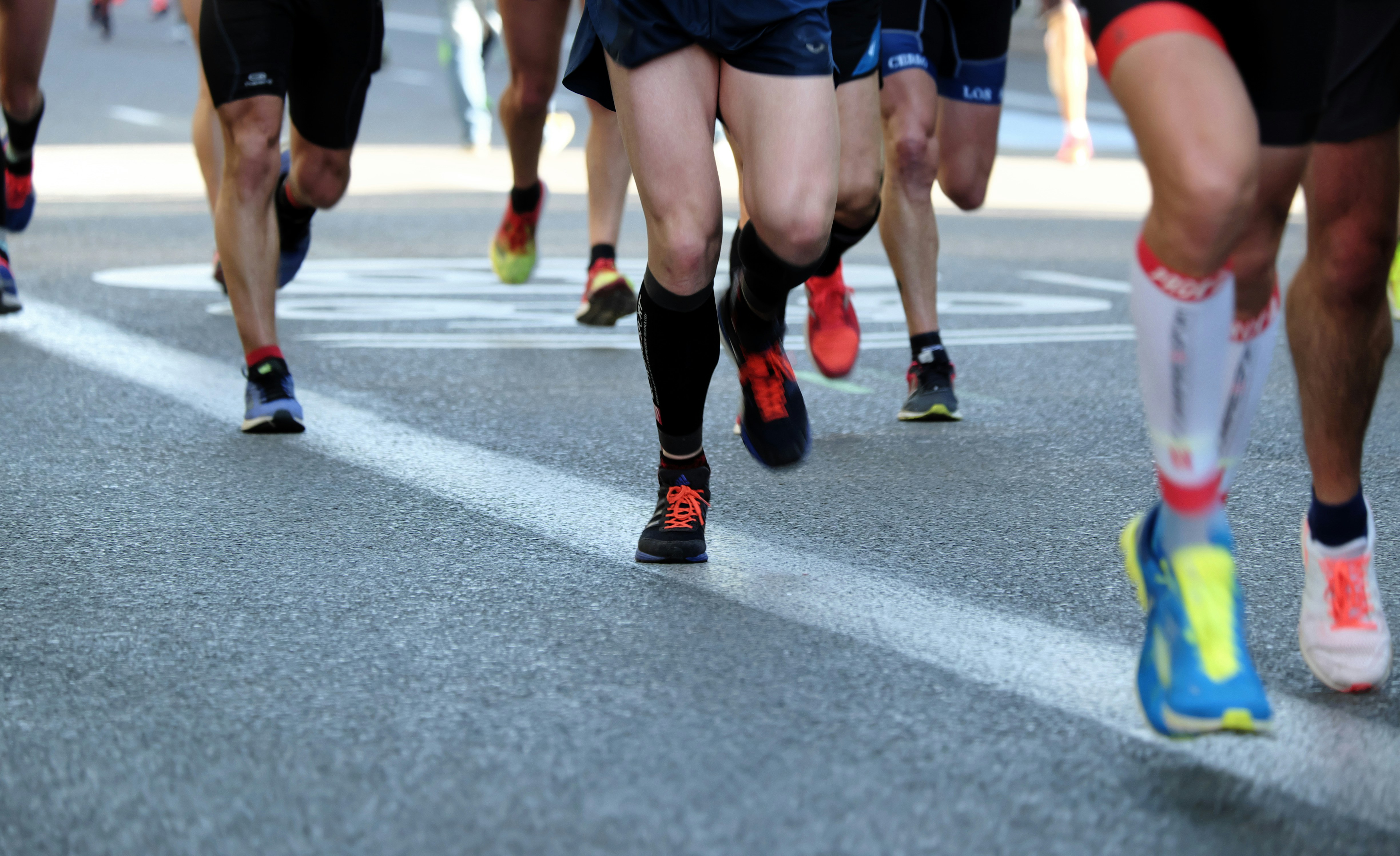 Image of people running on a tarmacked road, shown from the knee down.