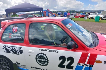 Nicola sat inside a red, white and blue Nissan Micra