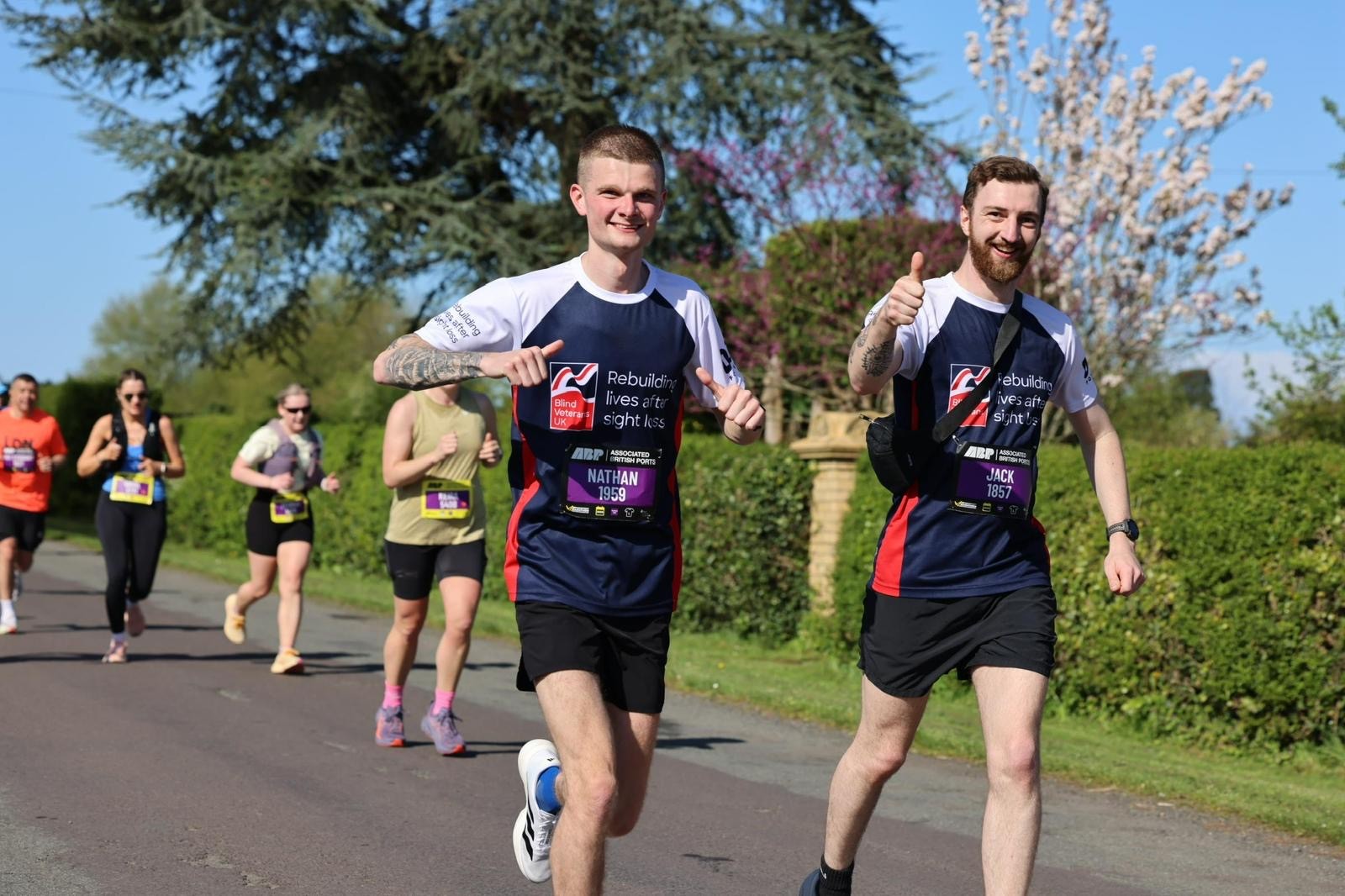 Zach and Jack giving a thumbs up and smiling as they run past the camera