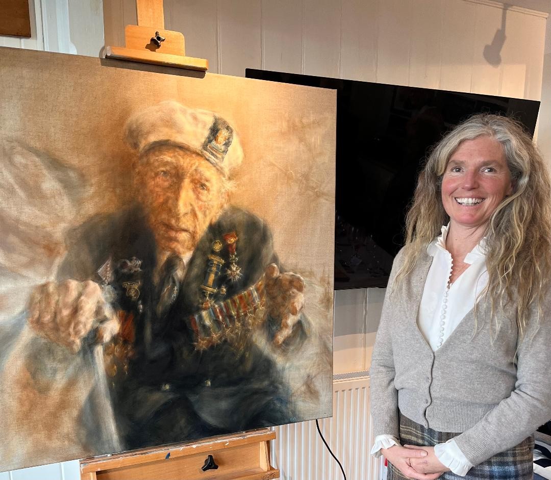 Francesca stands smiling next to the portrait of Alec