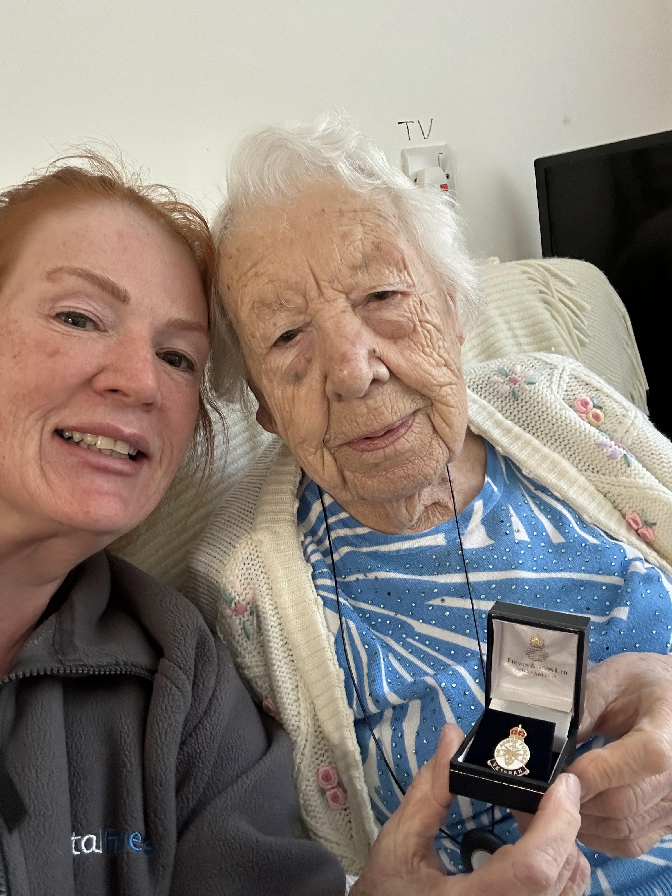 Olly holding her veterans badge while sitting next to volunteer Lanie.