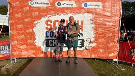 Jerry and Anne stood on a stage with a South Coast Ultra banner in the background