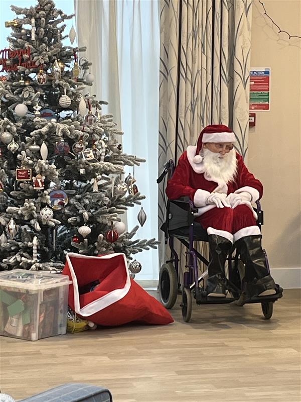 Father Christmas sits next to a Christmas tree at our Rustington centre