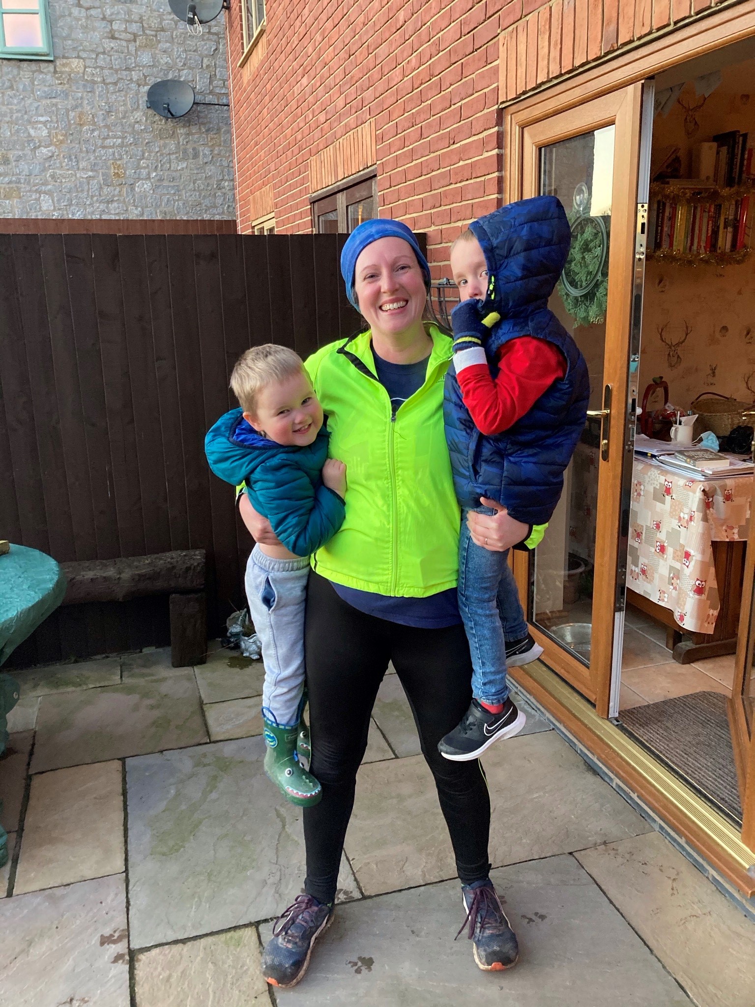 Charity supporter Sam, wearing running gear and holding up her two sons in her arms