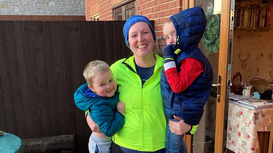 Charity supporter Sam, wearing running gear and holding up her two sons in her arms