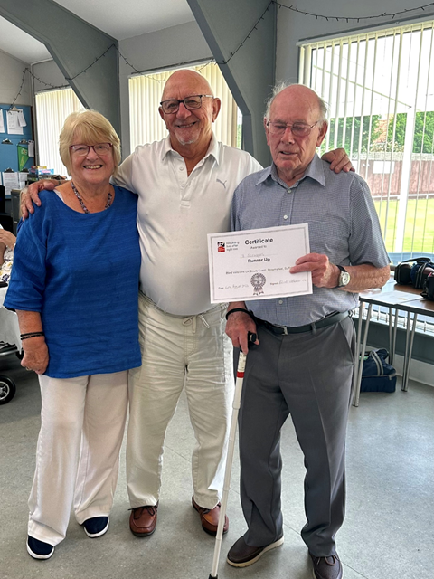 Veteran holding a certificate and standing with two other bowlers