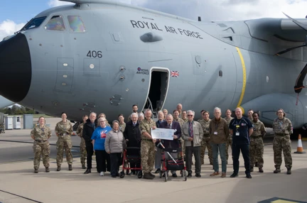 A large group photo of everyone involved in the Brize Norton visit including our veterans and staff and personnel from the military base. The group are stood in front of an A400M military transport aircraft