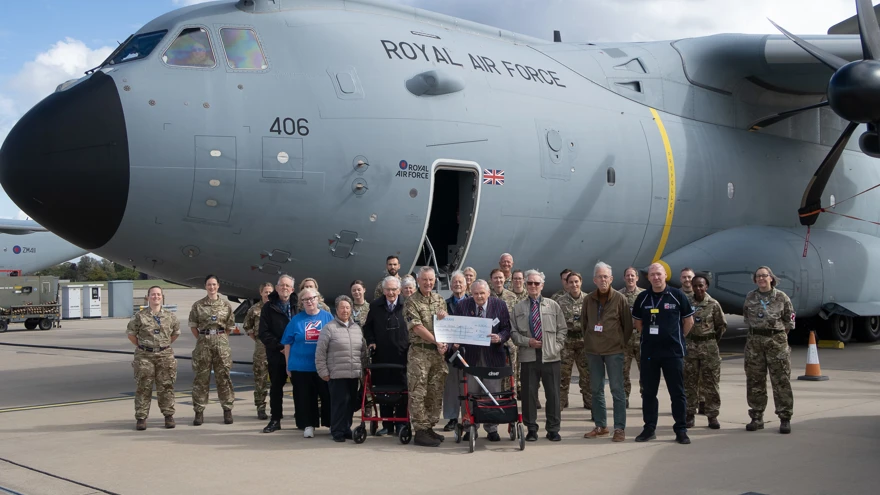 A large group photo of everyone involved in the Brize Norton visit including our veterans and staff and personnel from the military base. The group are stood in front of an A400M military transport aircraft