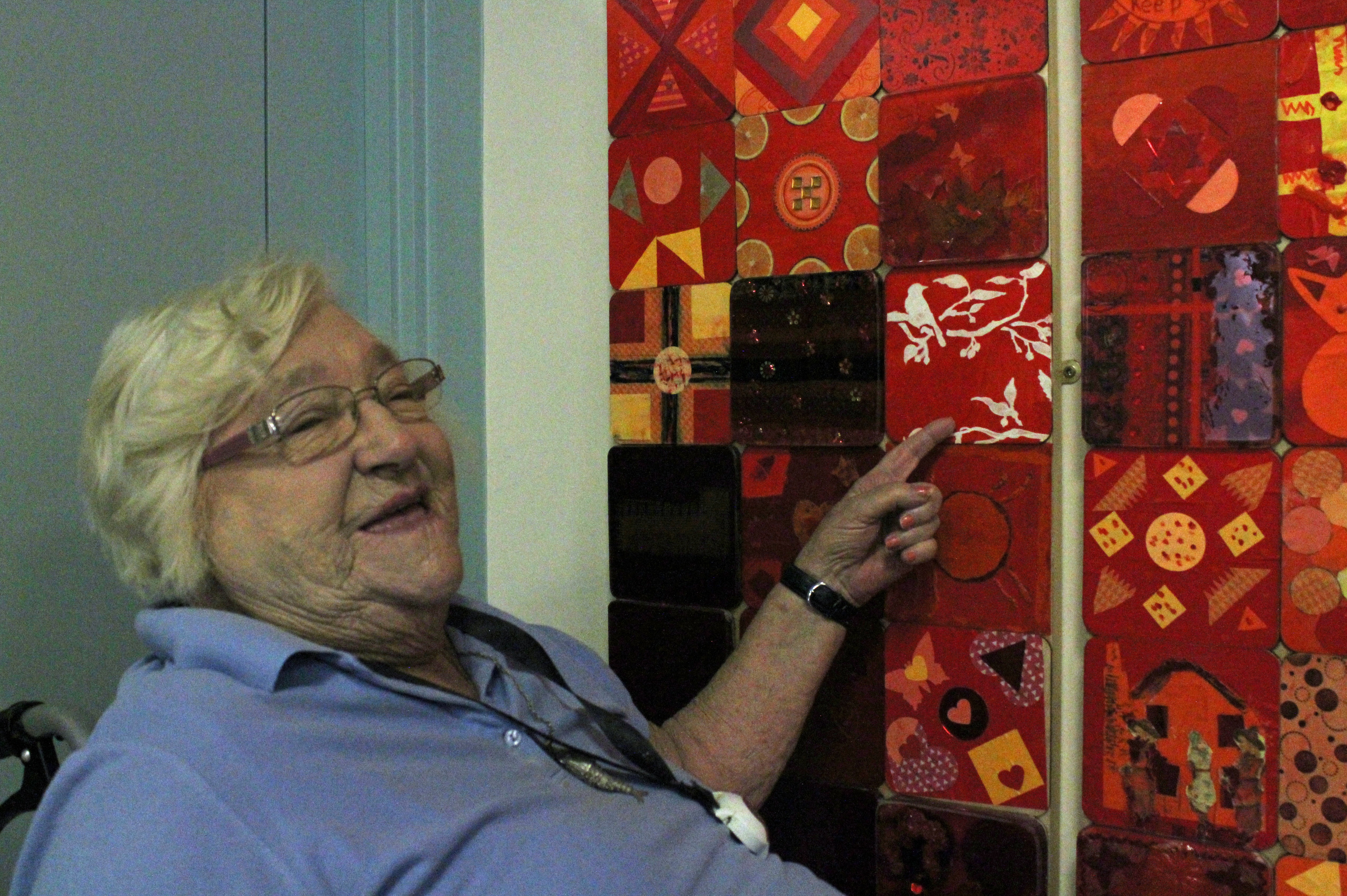Blind veteran, Win, smiling and pointing to her tile in the Collaboration in Colour artwork