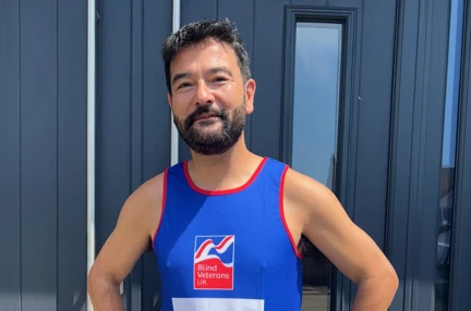 Jim stood with his hands on his hips smiling and wearing his Blind Veterans UK running top