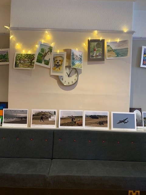Some of Bob's watercolour paintings hanging up and Brian's photographs below resting against the wall
