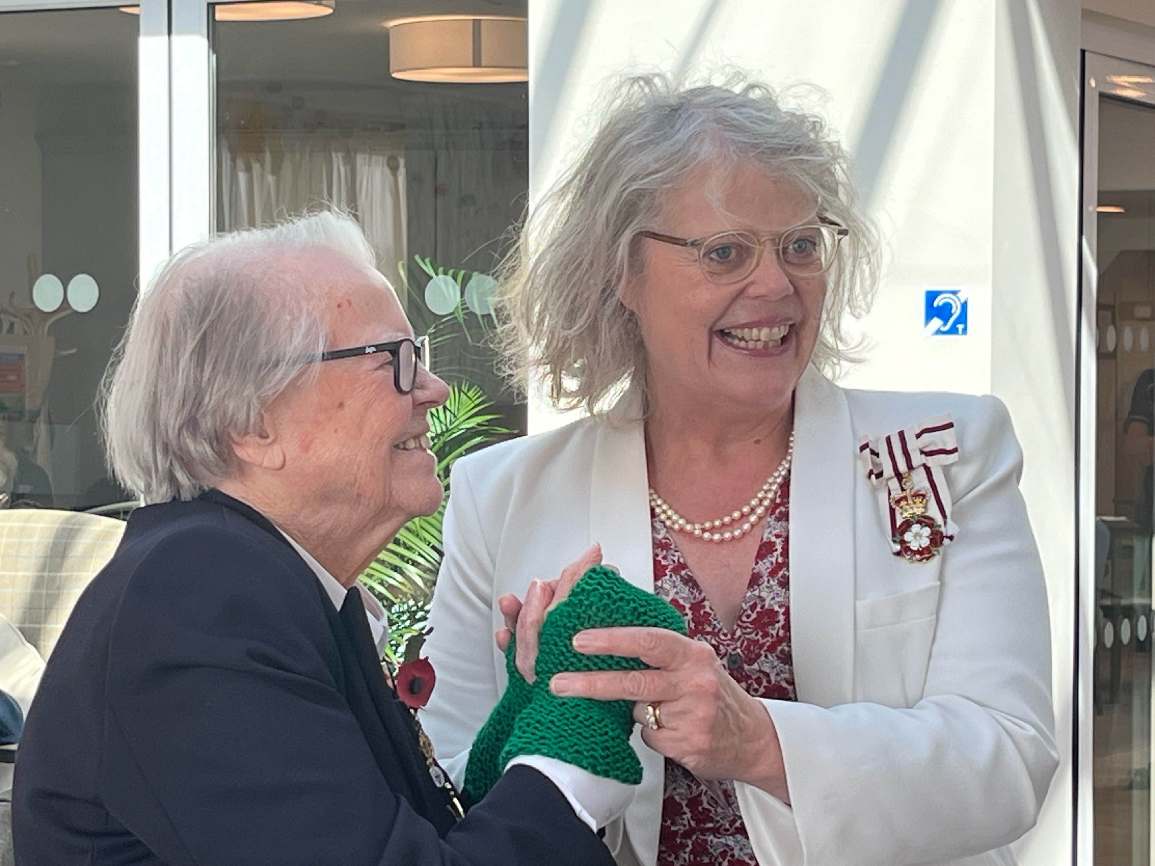 Lady Emma and Nancy holding hands with Nancy wearing the green knitted gloves she gifted to Lady Emma