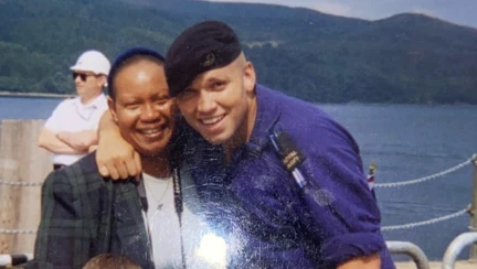 Herbie in uniform with his mother on a boat with mountains in the background