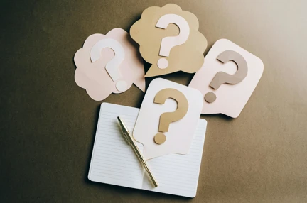 A photo of a notebook and question marks made out of craft paper