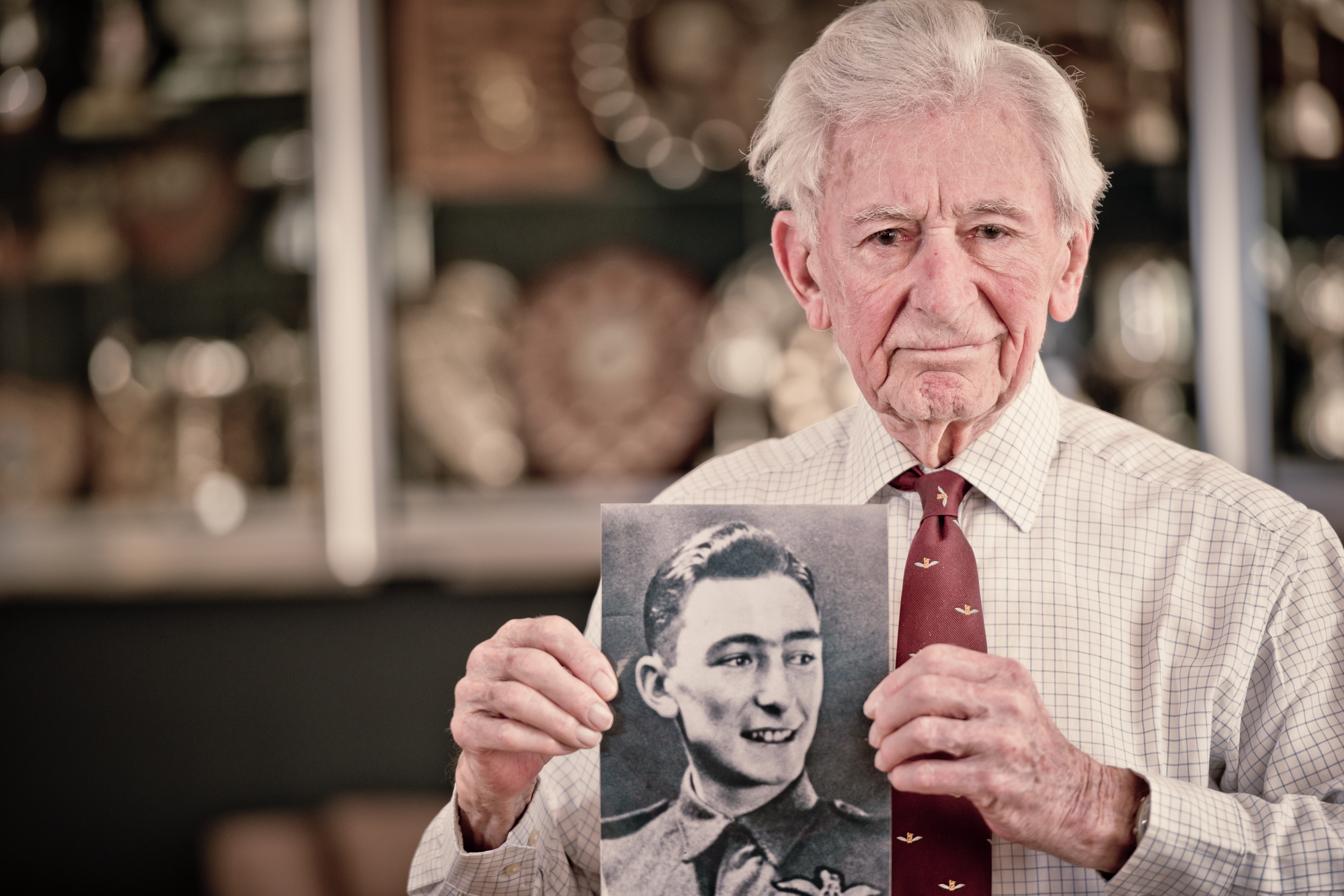 Blind veteran Jim holding a black and white photograph of himself during his days in service