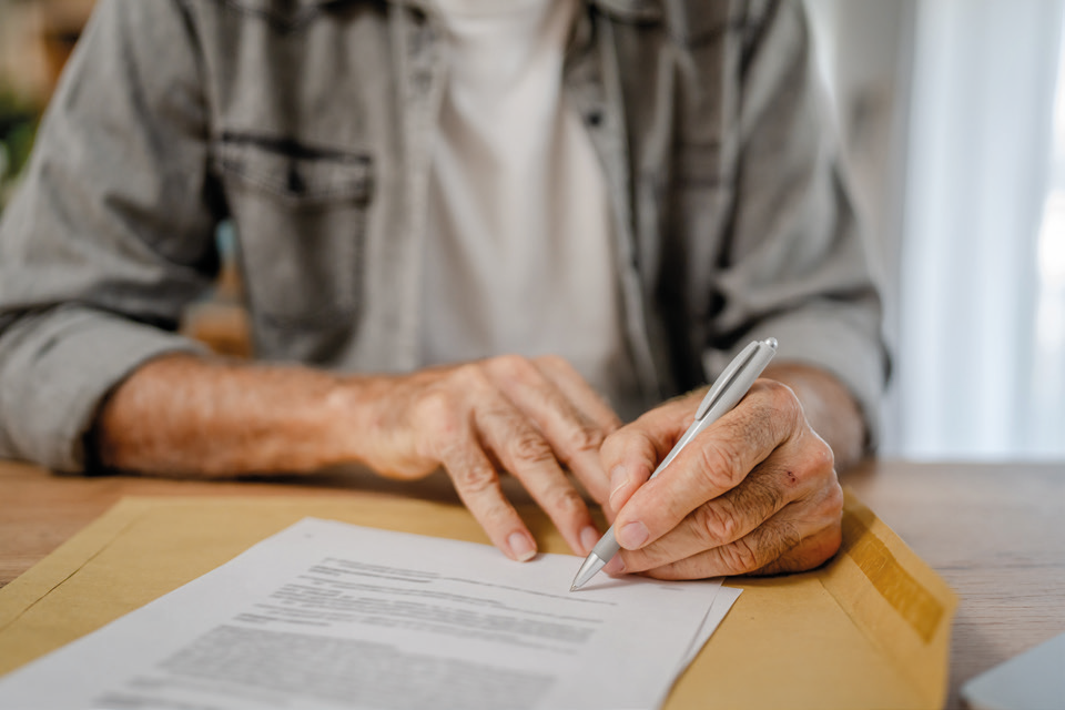 A stock photo of an elderly person signing a document