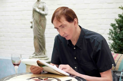 Blind veteran Robert sitting at a table looking over notebook