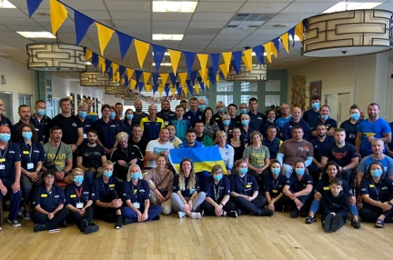 Group picture of Ukraine team with Blind Veterans UK staff sat under blue and yellow bunting