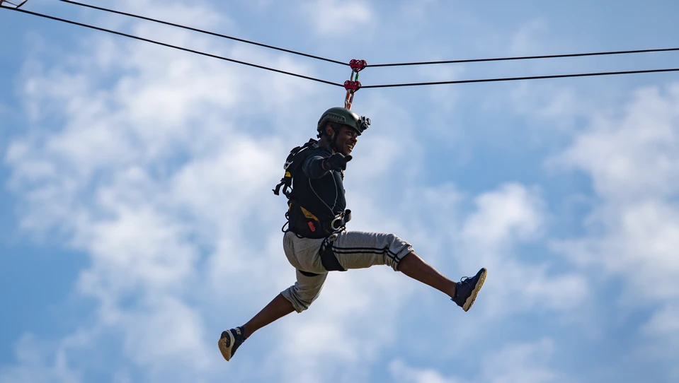 A photo of blind veteran Roan hanging on a zipline in the sky