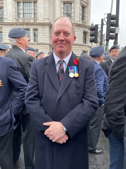 Giles stands with other veterans wearing a poppy and two medals