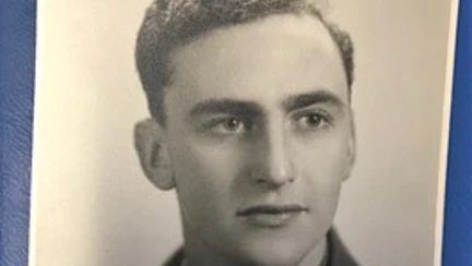 A black and white portrait of a young John during his days of service wearing his military uniform