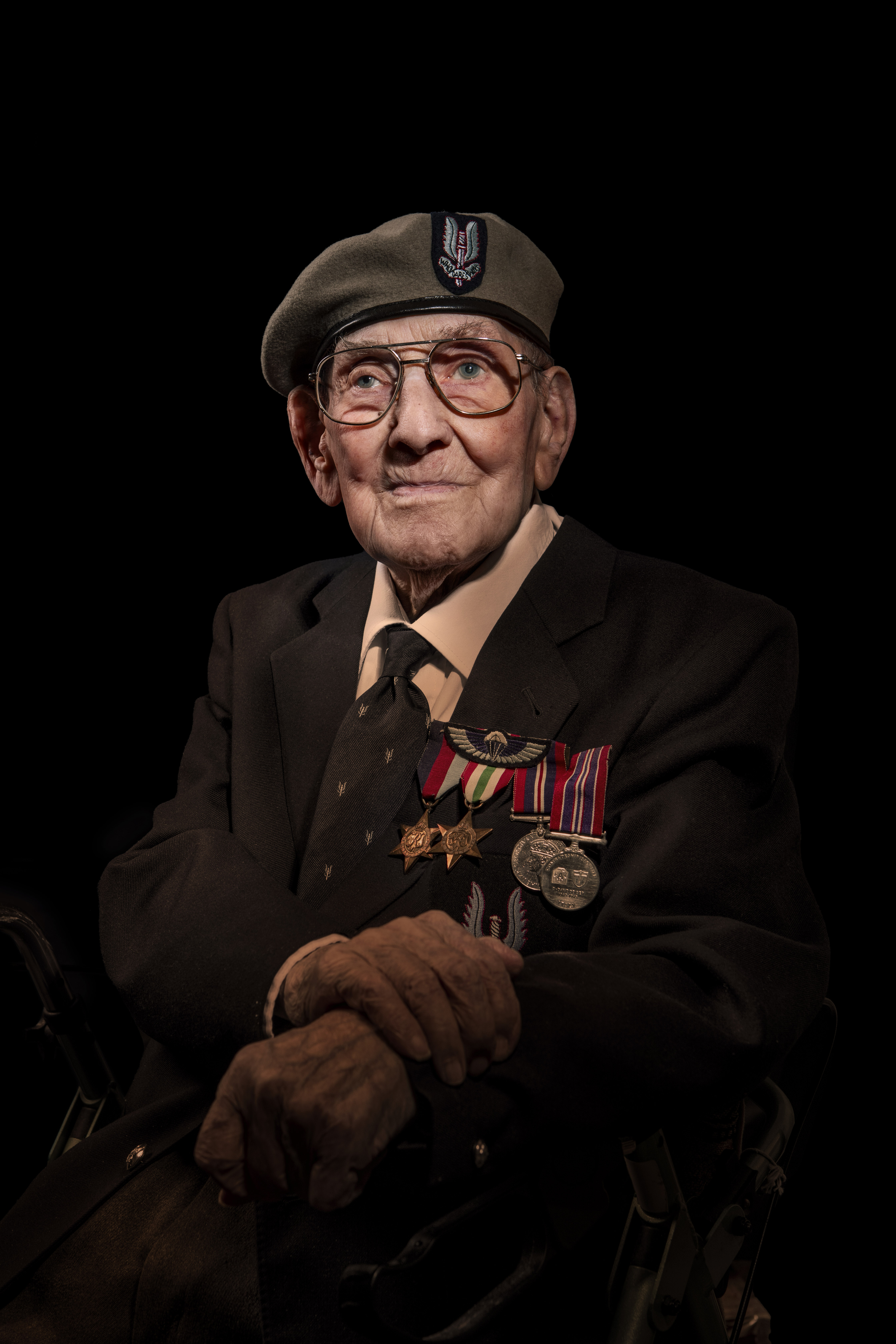 Matt photographed against a black background, wearing his badges and cap