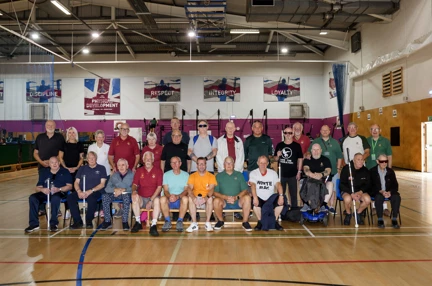 26 people group together for a team photo in a gymnasium
