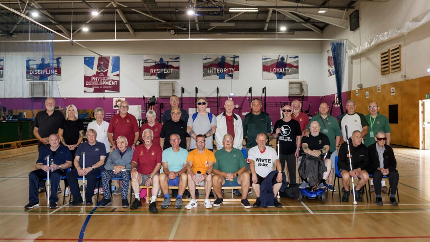 26 people group together for a team photo in a gymnasium