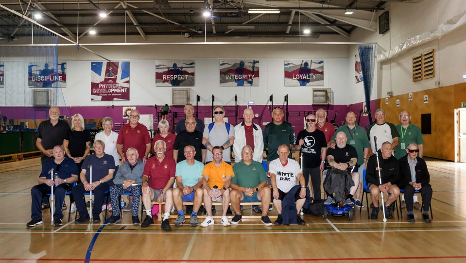 26 people group together for a team photo in a gymnasium