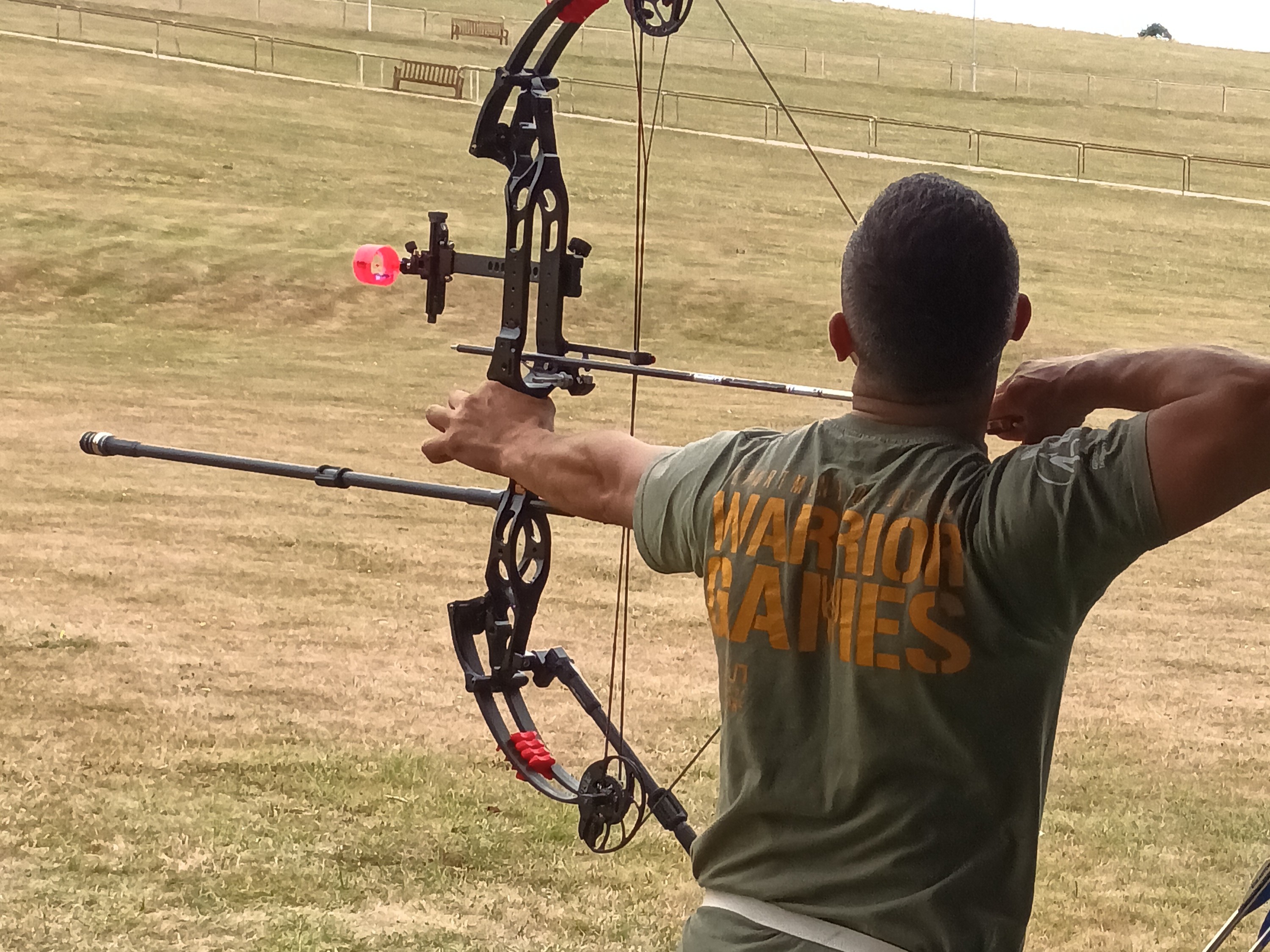 A Ukrainian athlete wearing a Warrior Games t-shirt practicing archery