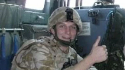 A young Ben in uniform sat in the back of an Army vehicle with his thumb up