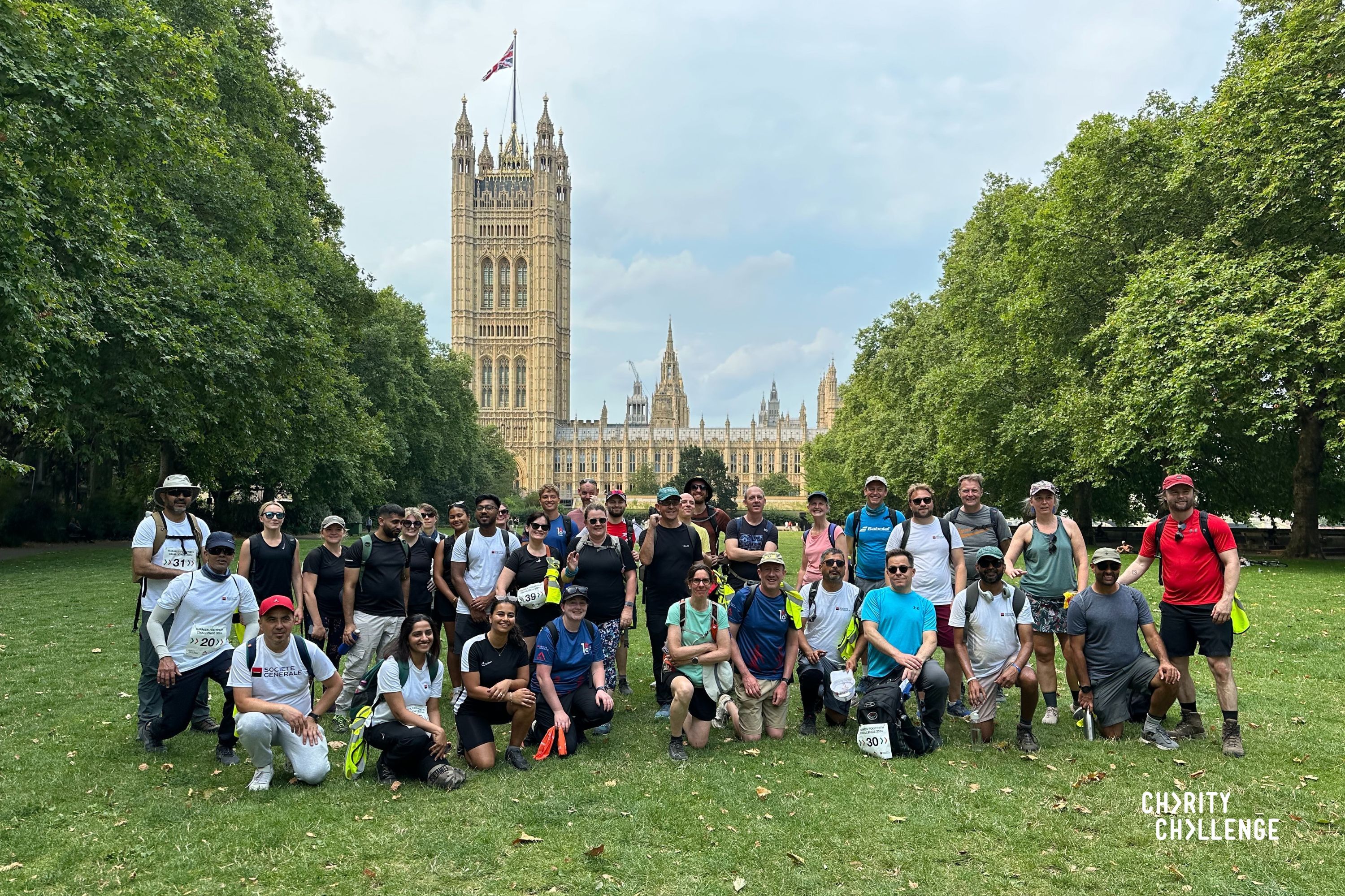 Group of happy, smiling walkers gathered together for a group photograph with the Houses of Parliament in the background