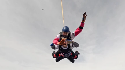 Oliva attached to colleague Jim during their skydive through a very cloudy sky