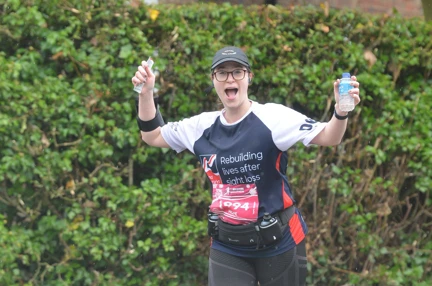 Hope pictured running outside waving her arms in the air, wearing a Blind Veterans UK training top