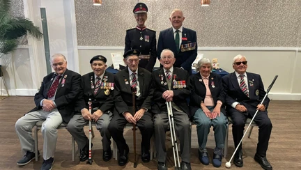 Six blind second world war veterans sitting on the front row with the Lord at the D Day 80 event in Swansea with the Lord Lieutenant of West Glamorgan and Veterans Commissioner for Wales standing behind