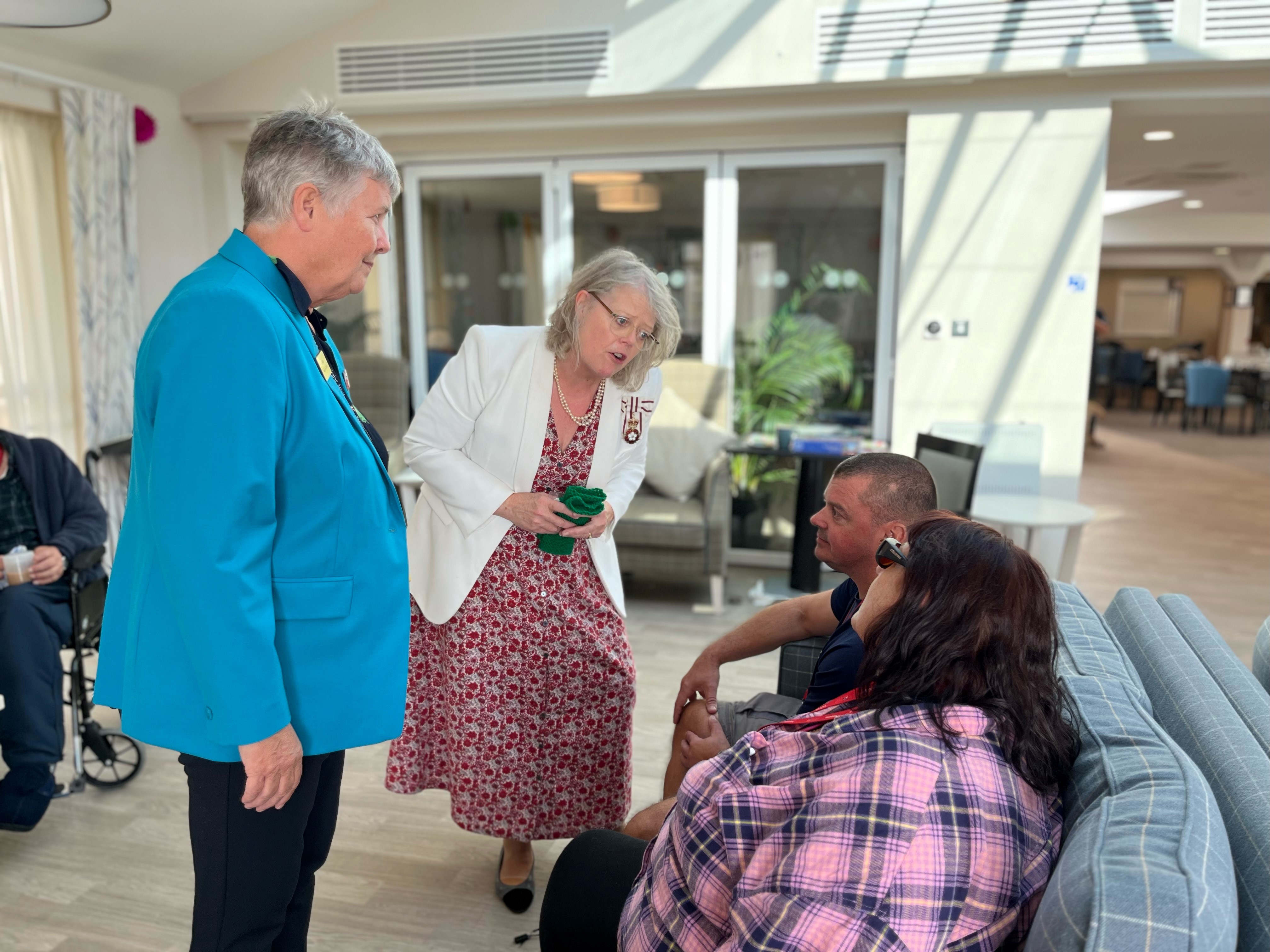Lady Emma and Centre Manager Lesley stood talking to Stuart and Mariam who are sat on the sofa in the Rustington Mess