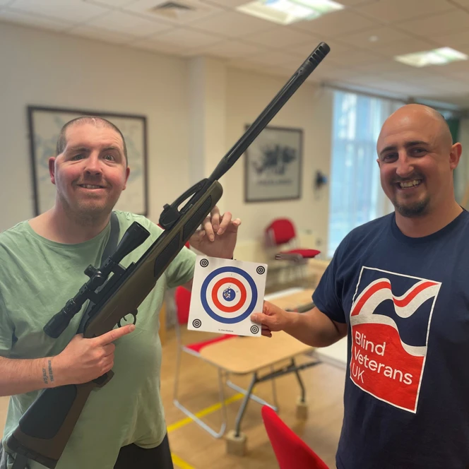 John holding a riffle and his target sheet