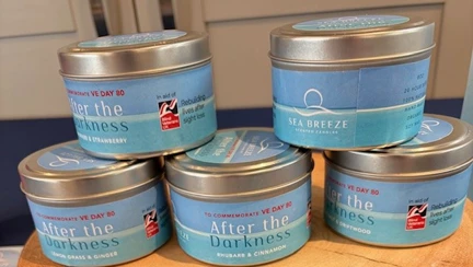 Five finished After the Darkness candles. The candle sits inside a metal tub stacked on one another.