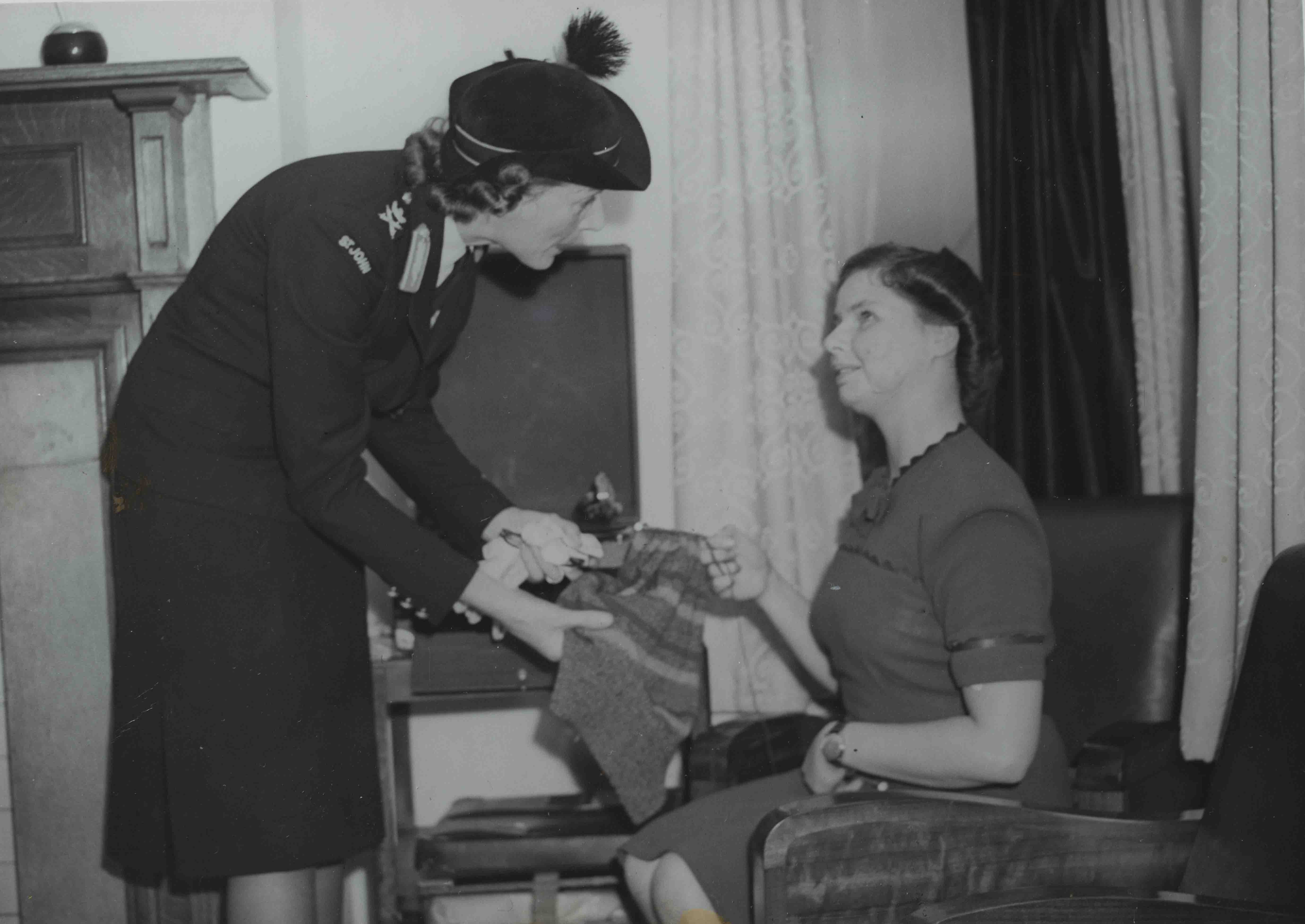 An archive photograph of blind veteran Barbara showing a woman in uniform her sewing work