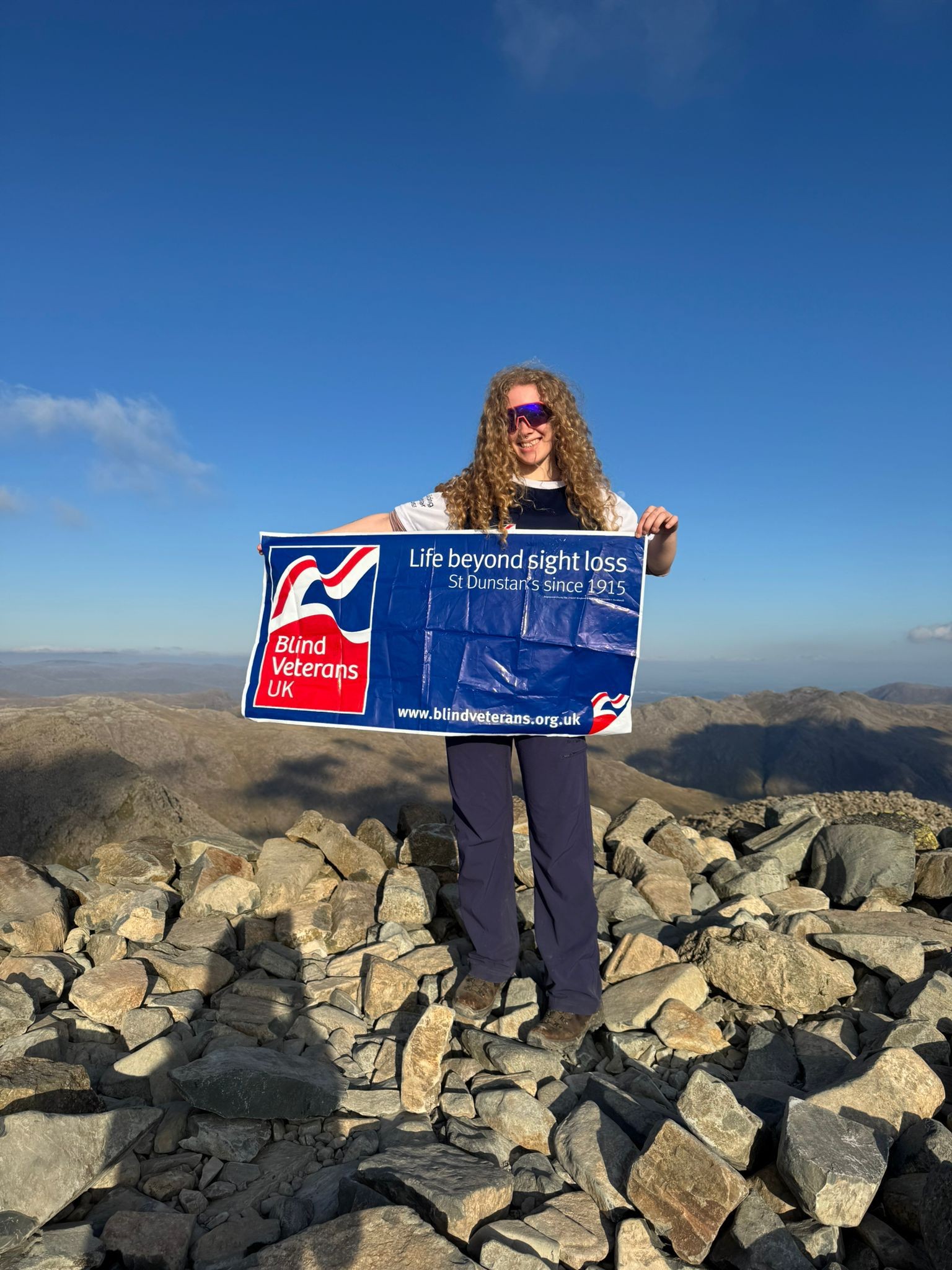 Anna holding the Blind Veterans UK banner with her hair being blown around in the wind