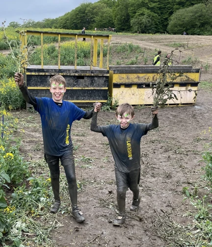 Sammy and Oakley holding hands and covered in mud from head to toe