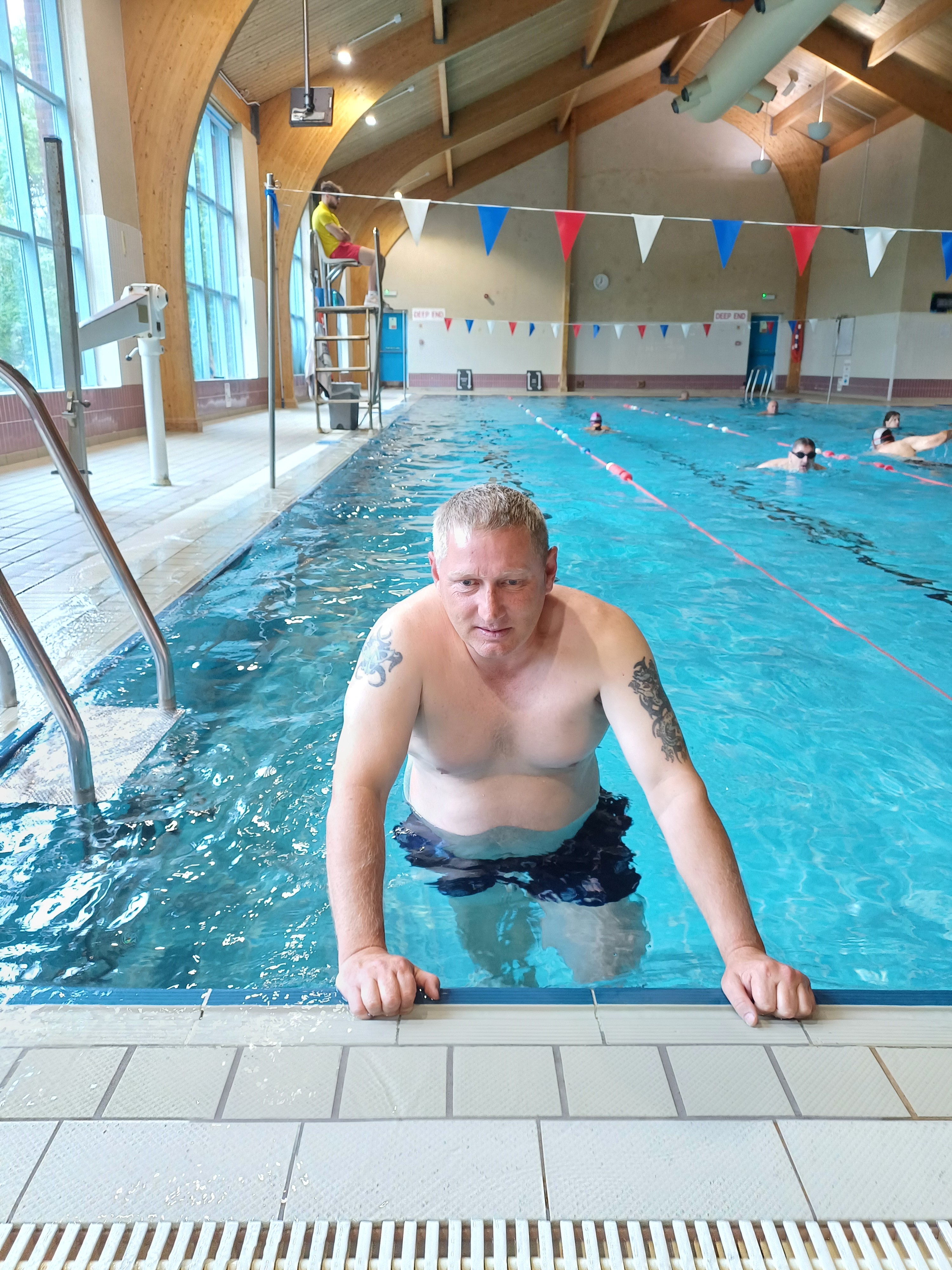 Lee in the pool leaning against the side for a photo