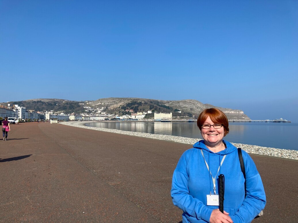 Blind veteran Sheila holding her cane while enjoying a walk at the coast