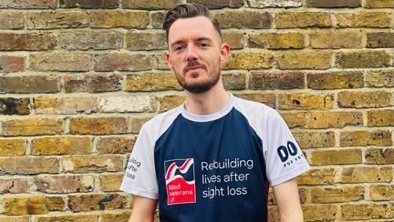 Rob stood in front of a brick wall in his Blind Veterans UK running top