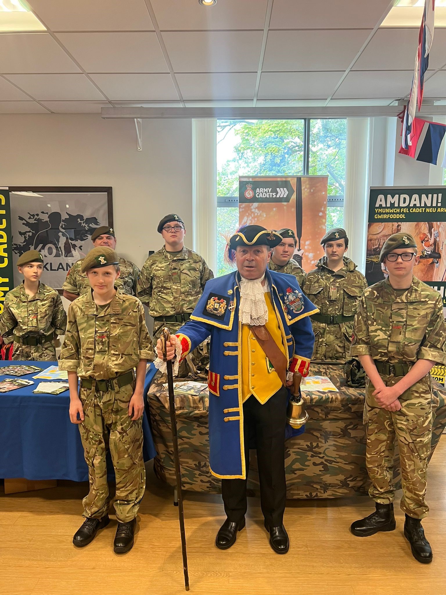 Billy in his town crier coat stood with uniformed Army Cadets at a table laid out with information about their organisation